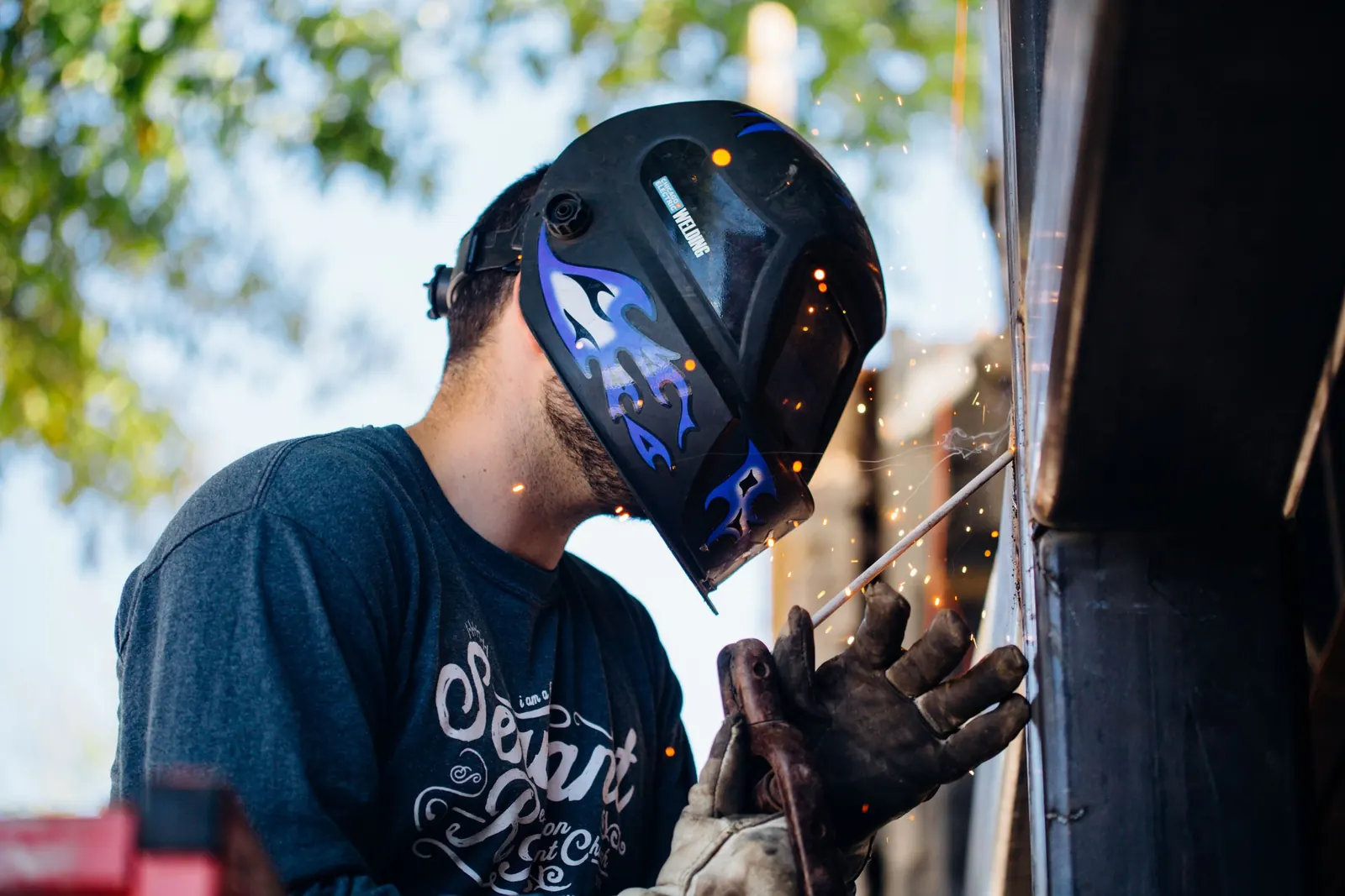 A welder in a welding mask working with sparks flying